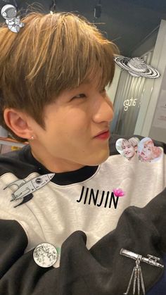 a young man with some hair clips in his hair and wearing a shirt that says jnjuin