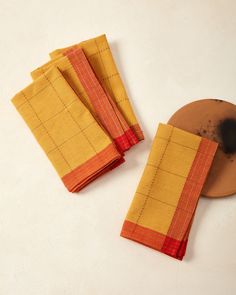 three yellow and red napkins sitting on top of a white table next to a brown plate