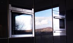 two ovens side by side in a kitchen with mountains in the backround