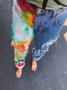 a woman in ripped jeans and sandals standing on the street with her leg wrapped around another person's waist