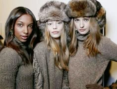 three models in fur hats and sweaters posing for the camera