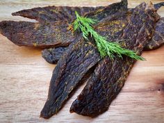 some kind of food that is on top of a wooden table with green sprigs