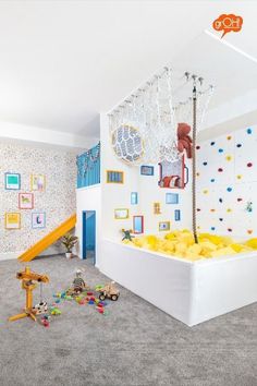 a child's play room with toys on the floor and climbing wall in the background