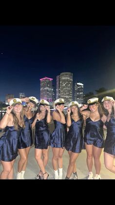 a group of women dressed in blue dresses posing for a photo with the city skyline behind them