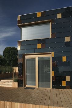 a wooden deck with a building that has been painted black and yellow