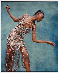 a woman in a dress with beads on her body and hands out to the side