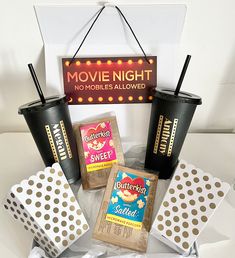 a table topped with two cups filled with coffee next to candy bars and popcorn bags