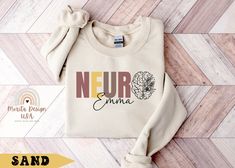 Our customizable Neuro shirt and sweatshirt make the perfect gift for those passionate about brain anatomy. Ideal for neurology nurses, doctors, specialists, interns, teachers, and students in the field of neurology. Personalize this garment with the nurse or doctor's name for a special touch. The unique design includes the option to add a brain with flowers, as shown in the image, making this piece both distinctive and meaningful. SIZE AND COLORS: Please refer to the color charts for the size a Neurology Nursing, Neuro Nurse, Nurse Brain, Anatomy Shirts, Nursing School Shirt, Grad Shirts, Nursing School Shirts, Doctor Names, Brain Anatomy