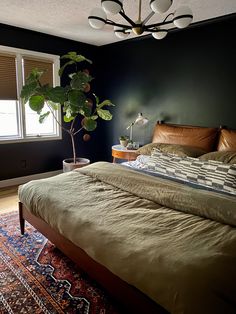 a large bed in a bedroom next to a window with a plant on top of it