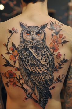 an owl tattoo on the back of a man's upper body, with flowers around it