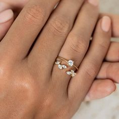 a close up of a person's hand holding an engagement ring with three diamonds