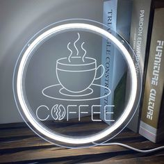 an illuminated coffee cup is on the table next to books and a book shelf with a lamp