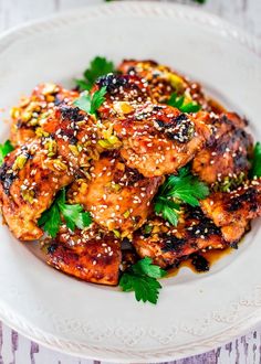 a white plate topped with chicken covered in sesame seeds and garnished with parsley