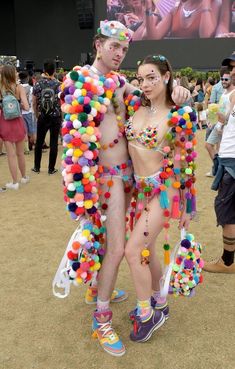 two people dressed up in colorful clothing at a music festival with balloons all over their body