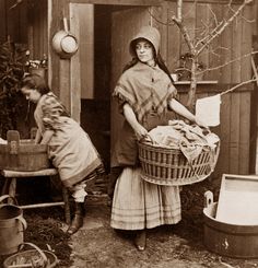 an old black and white photo of two women with laundry in their back yard, one holding a basket