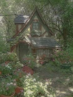 a house in the woods surrounded by flowers and trees