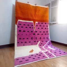 an orange and pink rug is sitting on the floor in front of a window,