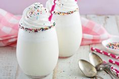 two glasses filled with whipped cream and sprinkles on top of a table