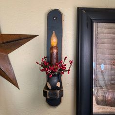 a candle is placed in a vase on the wall next to a framed photograph and star