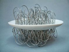 a white plate sitting on top of a table filled with metal wire wrapped around it