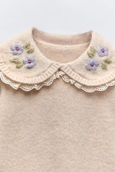 an image of a sweater with flowers on the collar and sleeves that are made out of wool