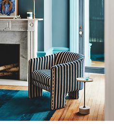 a striped chair sitting in front of a fire place next to a blue rug on a wooden floor