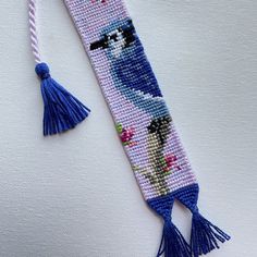 a beaded bookmark with a blue bird on it and a tassel hanging from the end