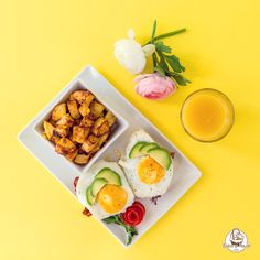 a plate with eggs, avocado and potatoes on it next to a glass of orange juice