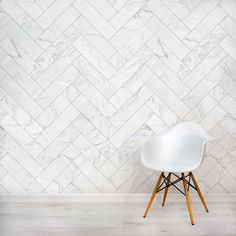 a white chair sitting in front of a wall with a herringbone pattern on it