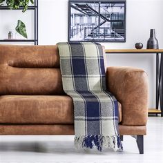 a brown leather couch with a plaid blanket on it