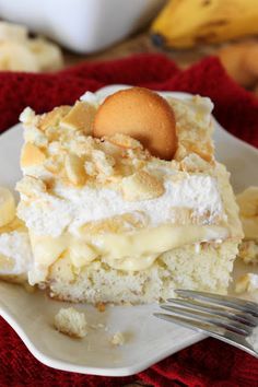 a piece of cake on a white plate with a fork next to it and bananas in the background