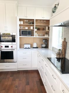 a kitchen with white cabinets and wooden floors