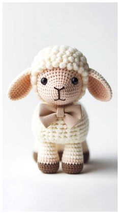 a crocheted sheep with a bow tie on it's head, sitting in front of a white background