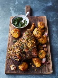 a wooden cutting board topped with meat and potatoes