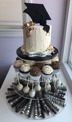 a tiered cake and cupcakes on a table