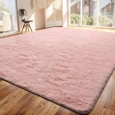 a large pink rug is in the middle of a room with wooden floors and windows