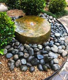 a water fountain surrounded by rocks and plants