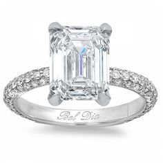 an emerald cut diamond engagement ring with pave diamonds on the band and side stones