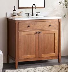 a bathroom vanity with a mirror above it and a rug on the floor next to it