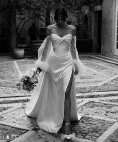 a woman in a white dress is walking down the street