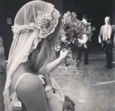 black and white photograph of a woman in wedding dress holding flowers next to a man