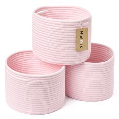 three pink braided storage baskets stacked on top of each other with a gold tag