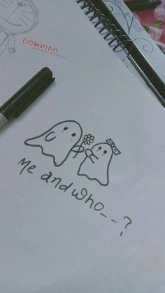 a notepad with a drawing of two ghostes on it next to a pen