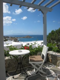 an outdoor table and chair on a patio overlooking the ocean