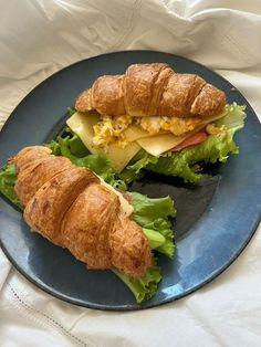 a croissant sandwich with cheese and lettuce is on a blue plate