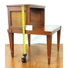 a small wooden table with a measuring tape on it and an end table next to it