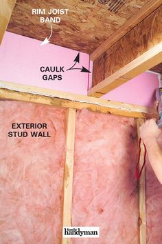 a man is working on insulation in a room with pink walls and exposed ceilinging