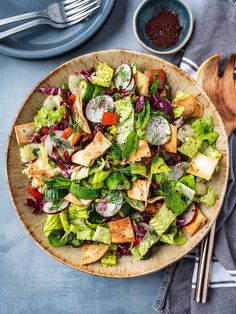 a salad with lettuce, carrots and other vegetables in a wooden bowl