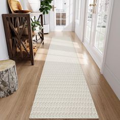 a long white rug on the floor in a room with wooden floors and large windows