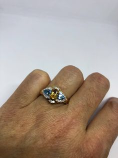 Vintage Golden Citrine Ring Deco Cocktail 925 Sterling Silver Unusual cut of citrine and blue topaz surrounded with white topaz Gold finished Sterling silver Setting Handmade Size 7 Can be resized by my jeweler for a $10-$20 jeweler's fee All rings are shipped free in the US in a nice gift box. Check out our over a THOUSAND great reviews Engraving is $4 per letter and is not always perfect depending on the piece. It can take a few days if the jeweler is busy. This is payable to Paypal Judithsltd Yellow Topaz Ring With Accent Stones, Three Stone Topaz Anniversary Ring, Anniversary Topaz Birthstone Gemstones, Multi-stone Blue Topaz Ring For Anniversary, Anniversary Multi-stone Citrine Topaz Ring, Luxury Gold Citrine Topaz Ring, Elegant Multi-stone Topaz And Citrine Ring, Multi-stone Citrine Topaz Ring, Yellow Topaz Emerald-cut Ring In Fine Jewelry